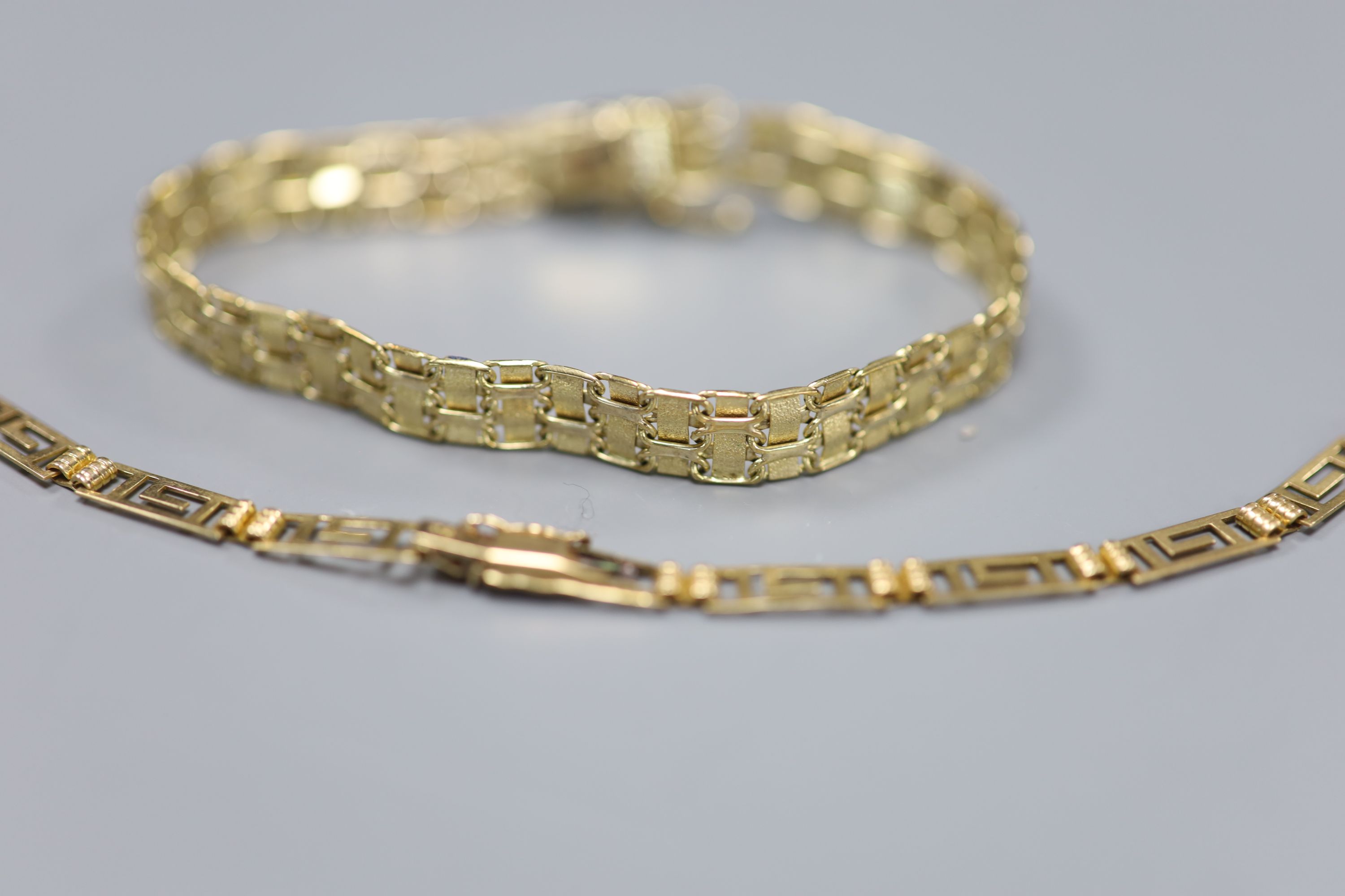 A 9ct plain and textured gold fancy link bracelet, 10.9g and a 585 yellow metal Greek key link bracelet (a.f.), 4.7g.